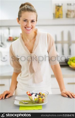 Smiling young housewife with fresh fruits salad