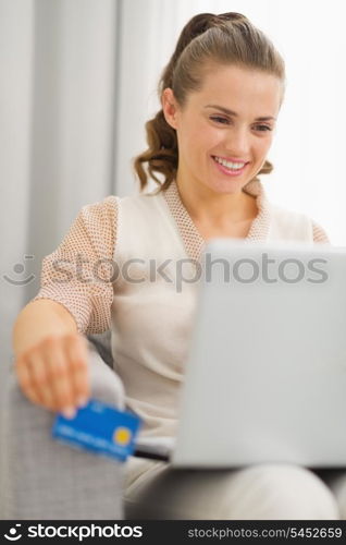 Smiling young housewife with laptop and credit card