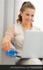 Smiling young housewife with laptop and credit card