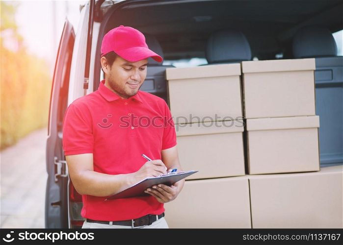 Smiling young male postal delivery courier man in beside of cargo van delivering package.Impressive service.