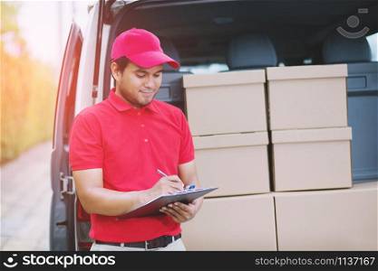 Smiling young male postal delivery courier man in beside of cargo van delivering package.Impressive service.