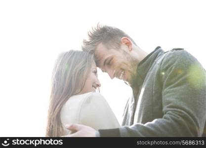 Smiling young man and woman embracing against clear sky