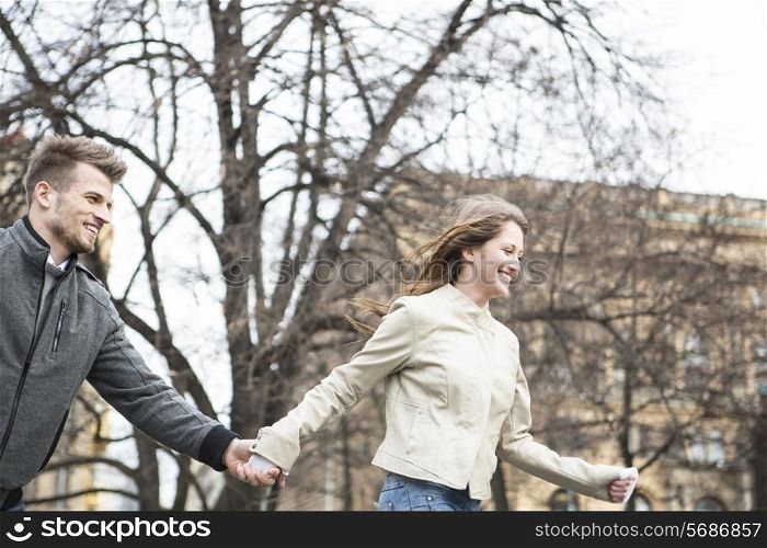 Smiling young man and woman holding hands and walking outdoors