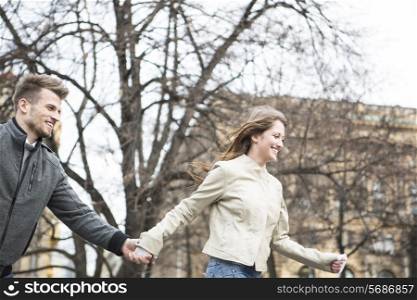 Smiling young man and woman holding hands and walking outdoors