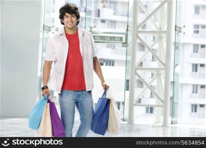 Smiling young man carrying shopping bags