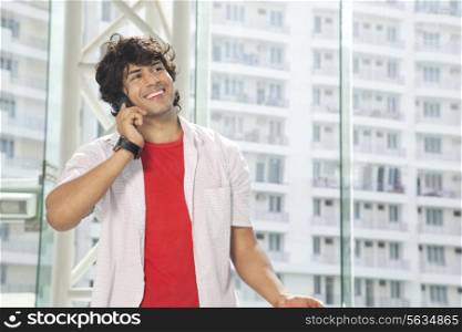 Smiling young man conversing on mobile phone