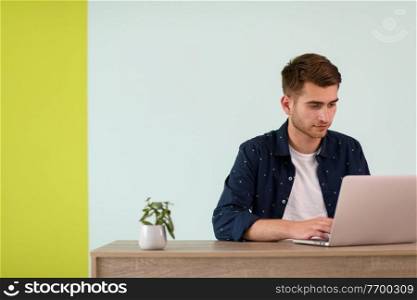Smiling young man freelancer using laptop studying online working from home, happy casual millennial guy typing on pc notebook surfing internet 
