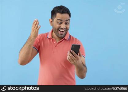 Smiling young man having fun while using Smartphone 