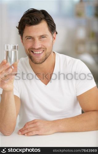 smiling young man holding a glass of water