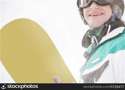 Smiling young man holding snowboard