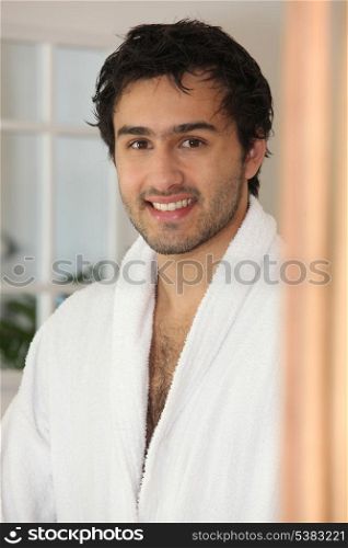 Smiling young man in a bathrobe
