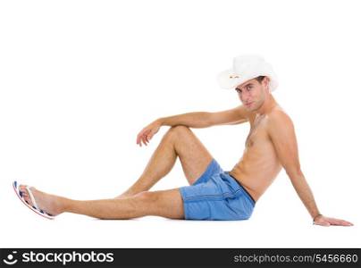 Smiling young man in shorts and hat sitting on floor