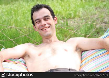 smiling young man lying on a hammock at the garden