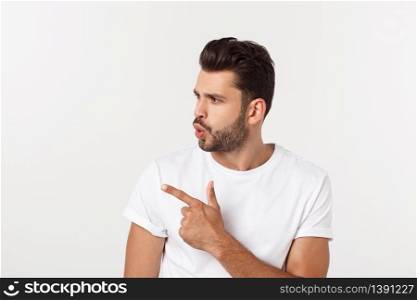 Smiling young man pointing finger against a white background. Smiling young man pointing finger against a white background.