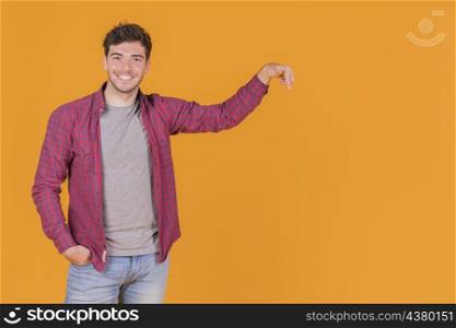 smiling young man pointing his finger upward against orange background