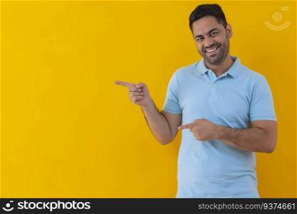 Smiling young man pointing sideways against yellow background