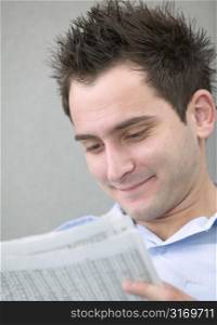 Smiling Young Man Reading Newspaper