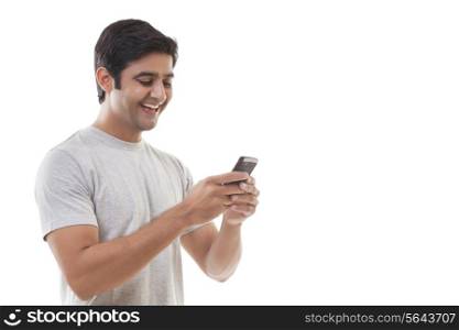 Smiling young man reading text message over white background