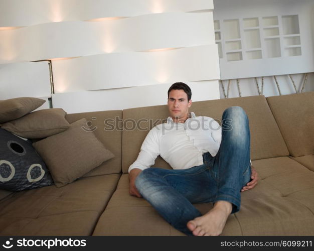 Smiling young man relaxing and dreaming on sofa at home