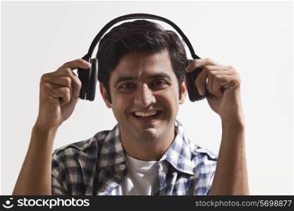 Smiling young man wearing headphones over colored background
