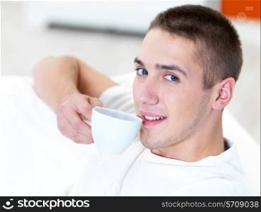 smiling young man with cup of coffee at home