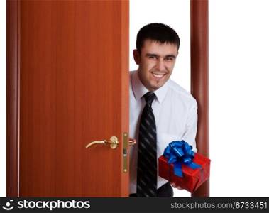 smiling young man with gift opening the door
