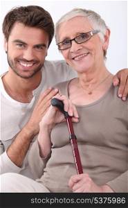 Smiling young man with his arms around a senior woman in glasses