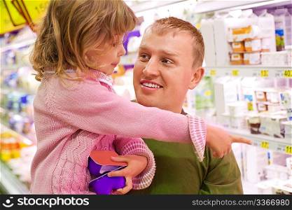 Smiling young man with little girl buy yogurt in supermarket