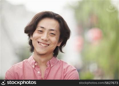 Smiling Young Man with Long Hair in Nanluoguxiang, Beijing, China
