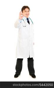 Smiling young medical doctor showing ok gesture isolated on white&#xA;