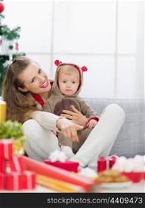 Smiling young mother spending Christmas with baby and pointing on copy space