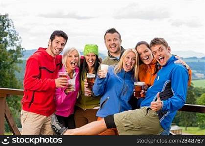 Smiling young people posing with beer and landscape background