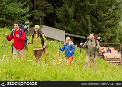 Smiling young people trekking in nature landscape with sticks