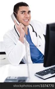 Smiling young physician sitting at his desk talking over phone in white background