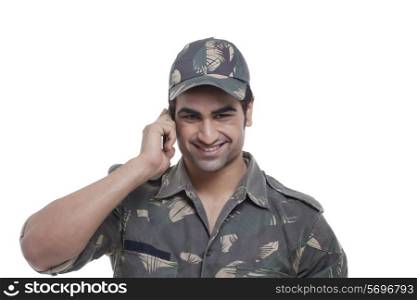 Smiling young soldier having conversation on mobile phone over white background