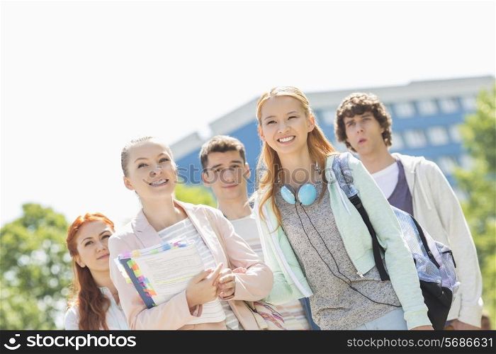 Smiling young students standing together at college campus