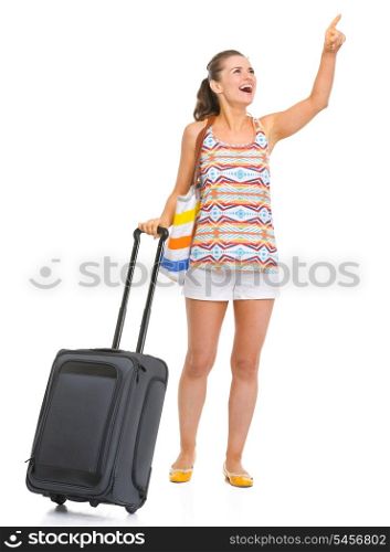 Smiling young tourist woman with wheel bag pointing on copy space