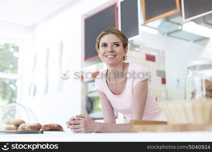 Smiling young waitress leaning on counter at restaurant