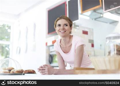 Smiling young waitress leaning on counter at restaurant