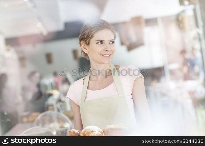 Smiling young waitress serving fresh bread at restaurant