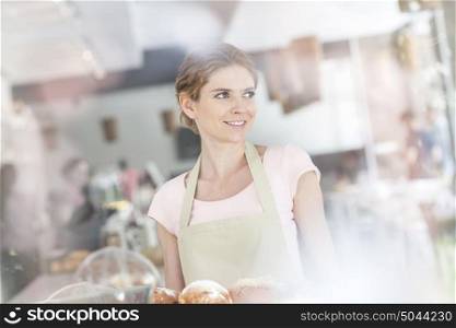 Smiling young waitress serving fresh bread at restaurant