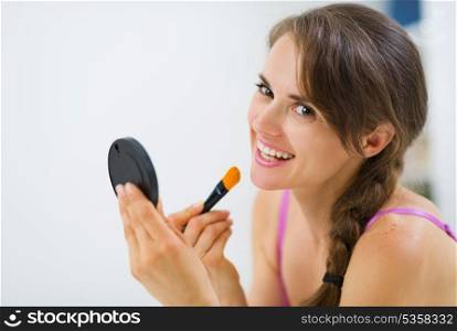 Smiling young woman applying makeup