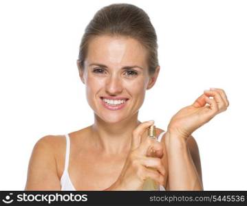 Smiling young woman applying perfume on hand