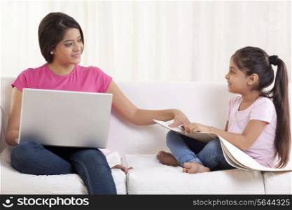 Smiling young woman assisting her daughter in drawing