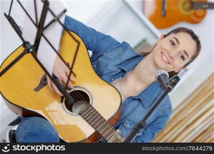 smiling young woman at home with guitar