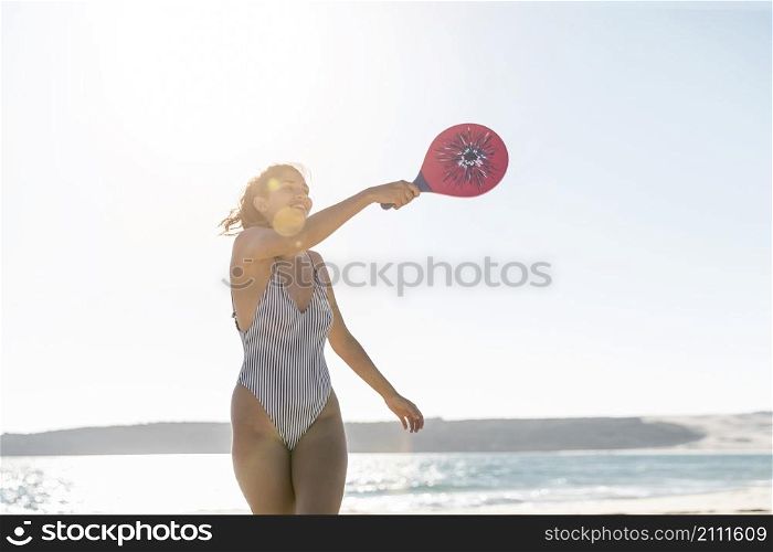 smiling young woman beach playing tennis