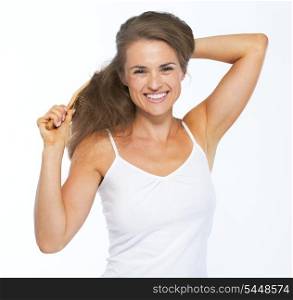 Smiling young woman combing hair
