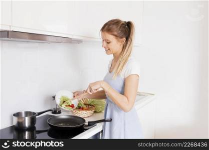 smiling young woman cooking vegetables kitchen