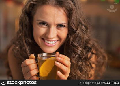 Smiling young woman drinking ginger tea with lemon