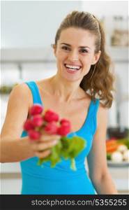 Smiling young woman giving bunch of radishes